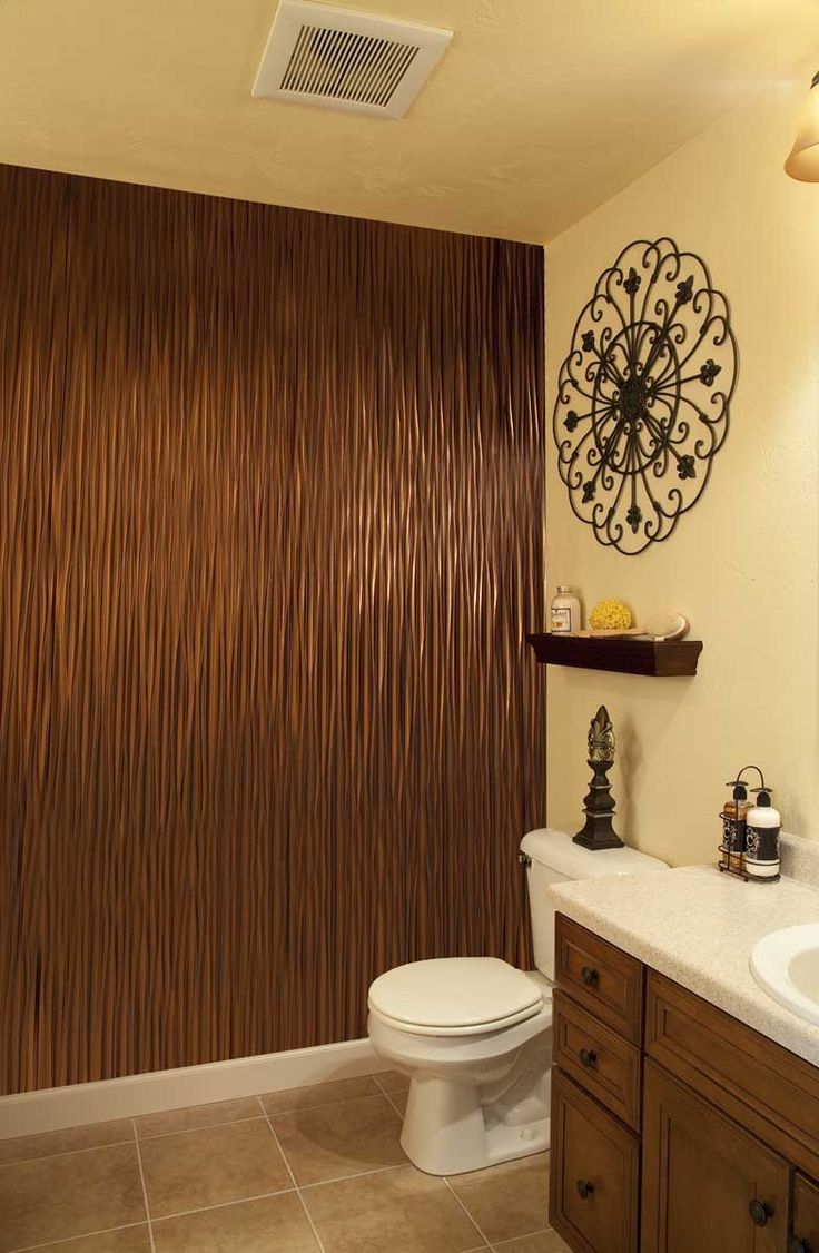 a bathroom with a toilet, sink and brown wall paper on the shower curtain behind it