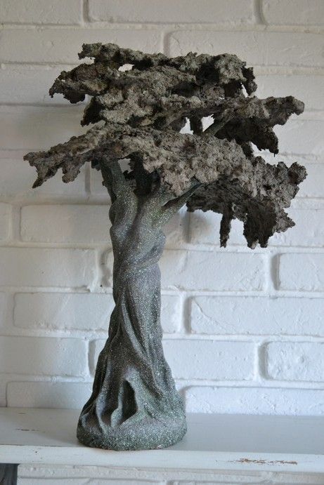 a bonsai tree sitting on top of a white shelf next to a brick wall