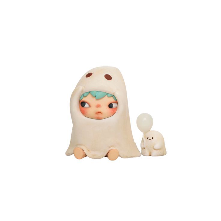 a toy with a small white dog next to it on a white surface and an object in the shape of a ghost