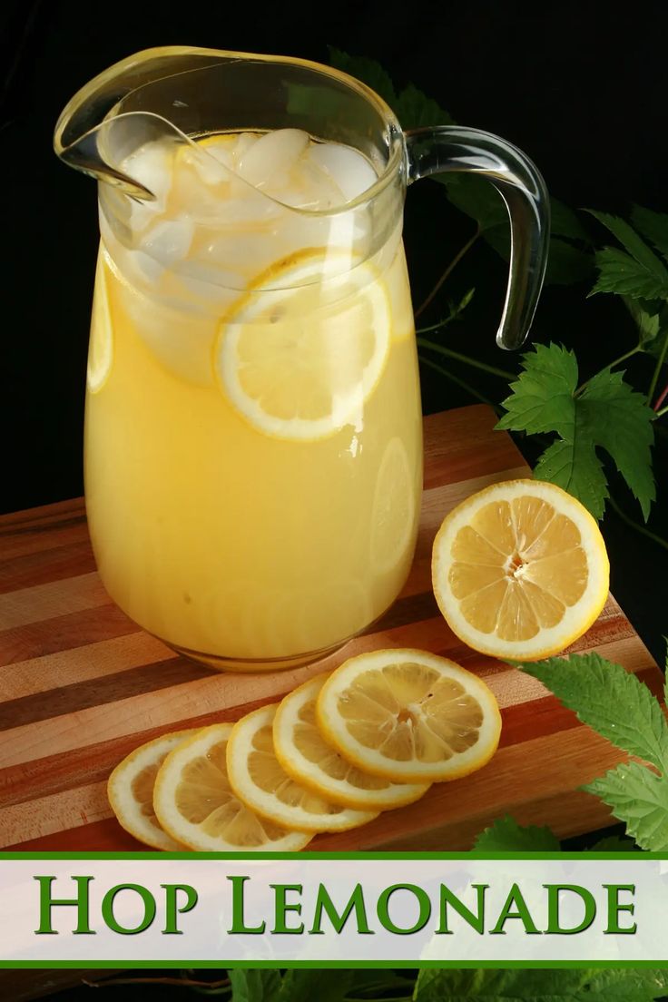 a pitcher filled with lemonade sitting on top of a cutting board next to sliced lemons