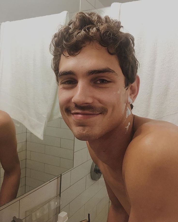 a shirtless man is taking a selfie in front of the bathroom mirror with his moustache