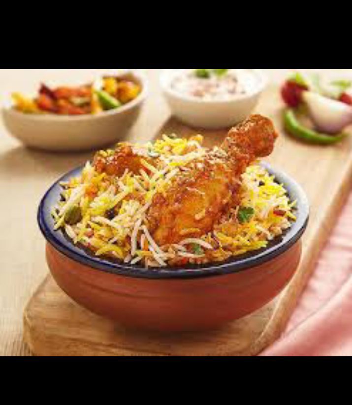 a bowl filled with chicken and rice next to bowls of other food on a table