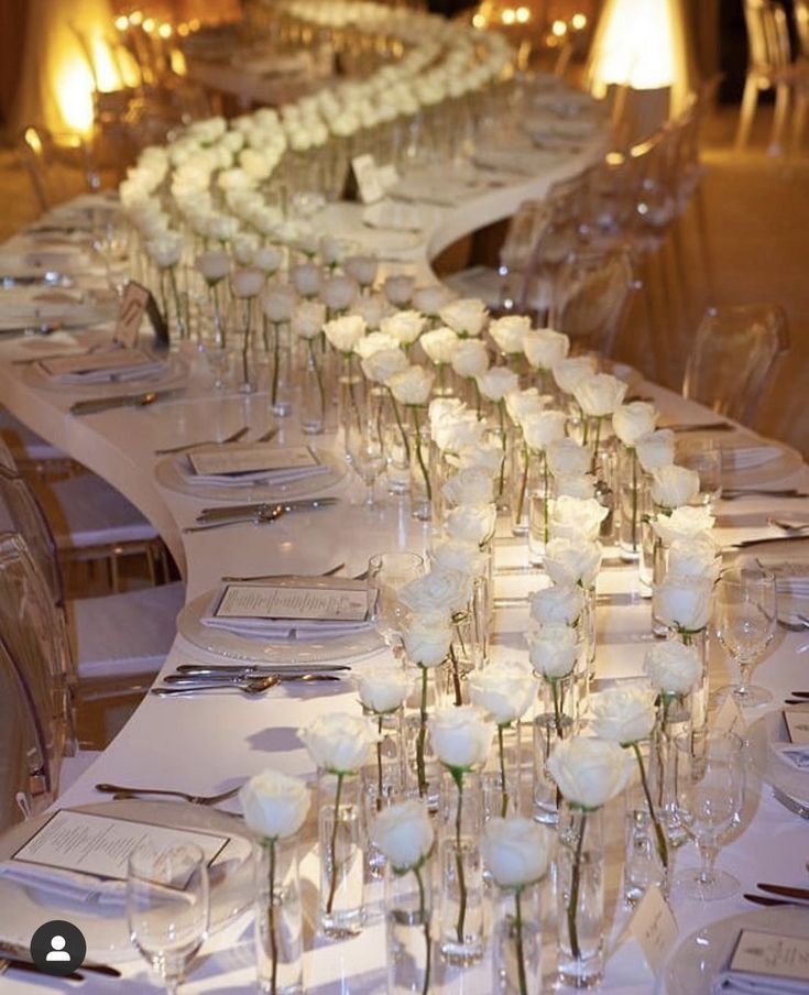 a long table is set with white roses and place settings for the guests to sit down