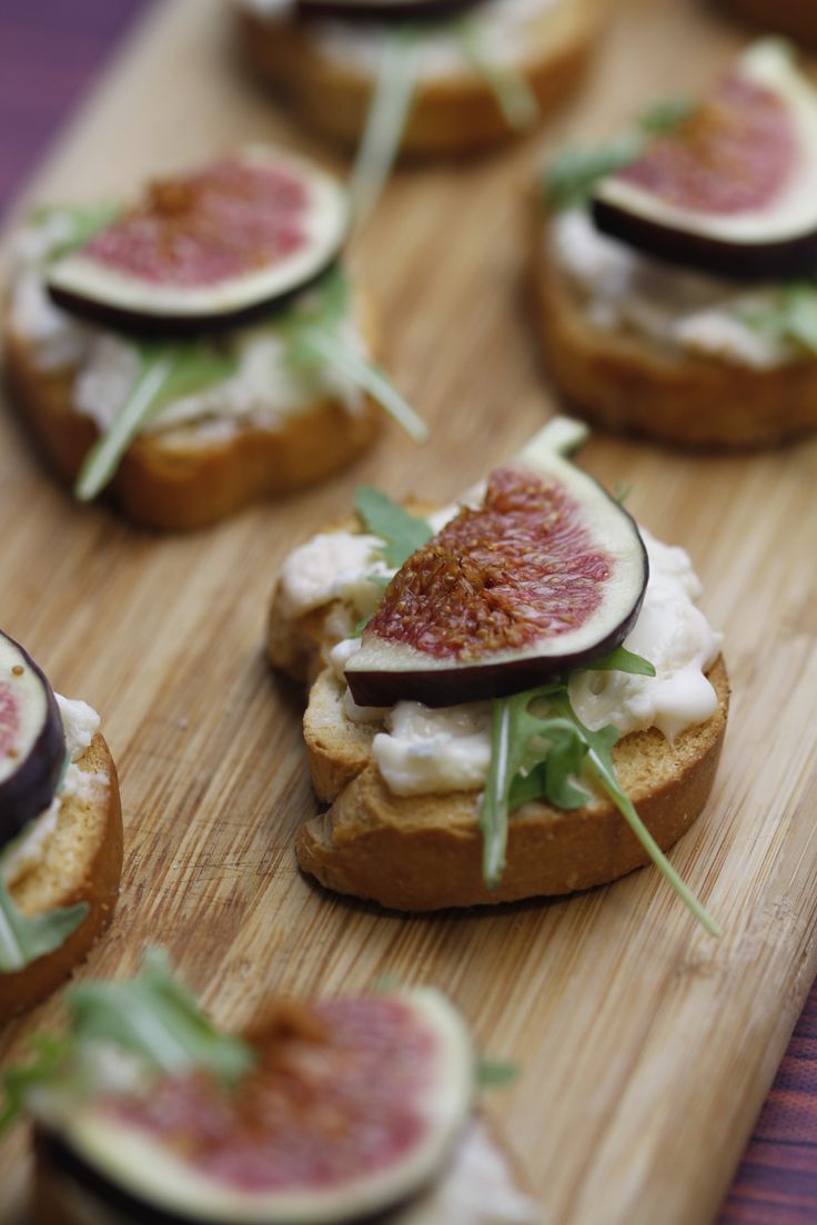 small sandwiches with figs and cream cheese are on a cutting board, ready to be eaten