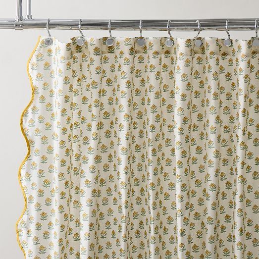 a shower curtain with yellow trim hanging from a metal bar in front of a white wall