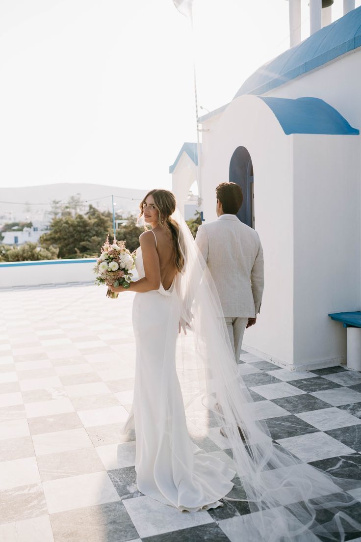 a bride and groom standing in front of a church with the sun shining on them