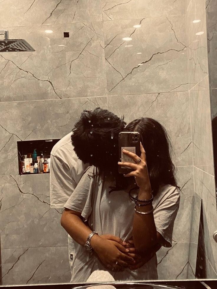 a man and woman taking a selfie in front of a bathroom mirror with the reflection of them