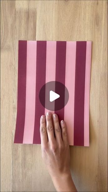 someone is making a pink and red striped piece of paper with the video below it