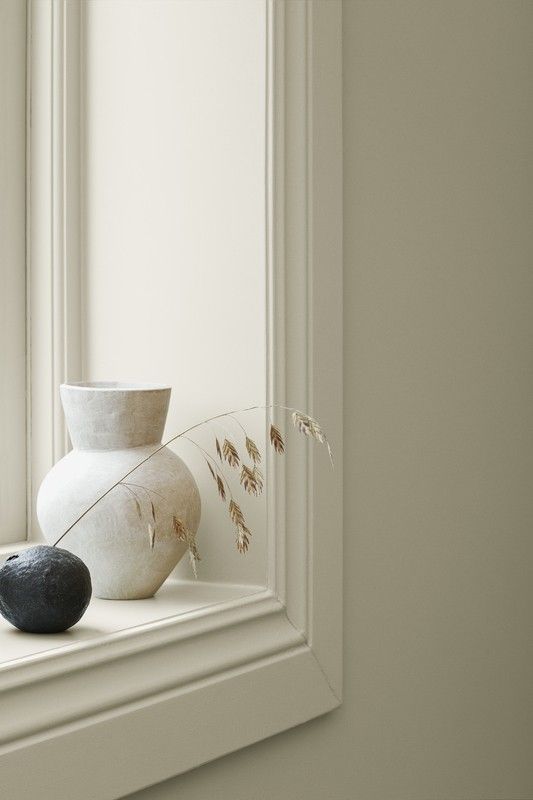 a white vase sitting on top of a window sill next to a black rock