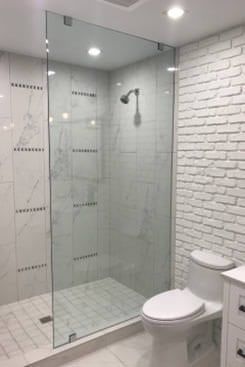 a bathroom with a toilet, sink and shower stall in white tile on the walls