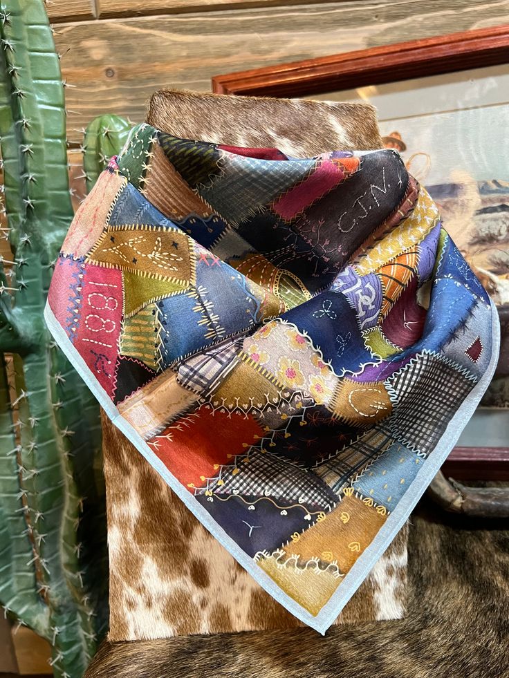 a close up of a cow's head with a bandana on it and a cactus in the background