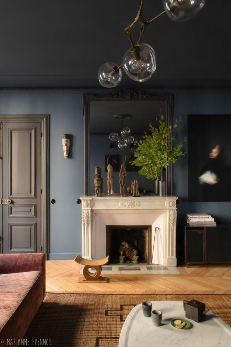 a living room filled with furniture and a fire place under a chandelier above a fireplace