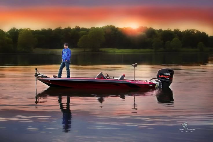 a man standing on top of a red boat in the middle of a body of water