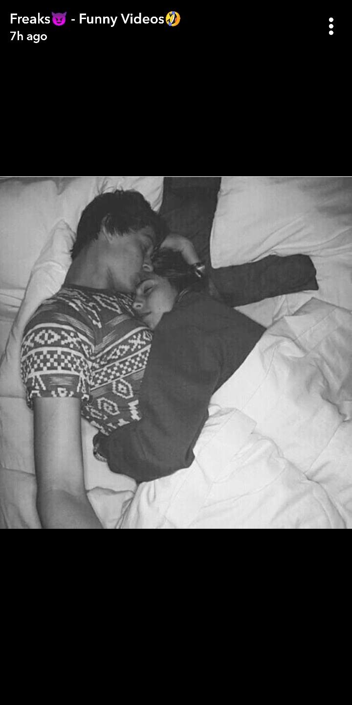 a man sleeping on top of a white bed next to a woman in a black and white photo