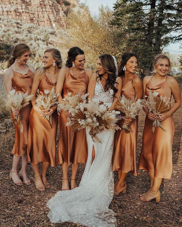 a group of women standing next to each other in front of some tall trees and grass