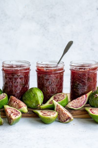 figs and jam in jars on a wooden board with the words pistachio