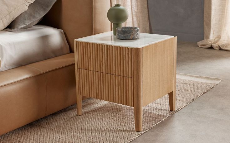 a small table with a vase on it next to a couch in a living room