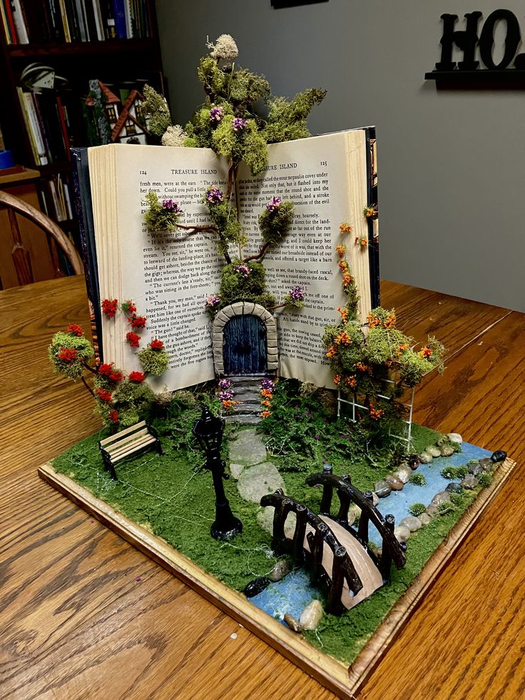 an open book sitting on top of a table covered in fake flowers and plants,