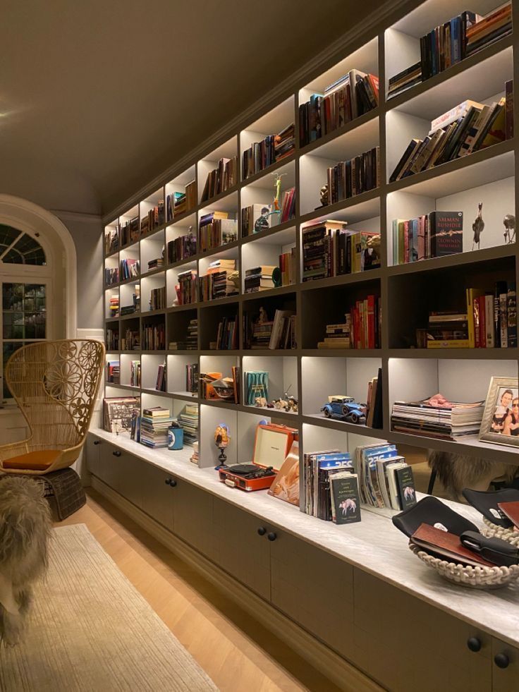 a room filled with lots of books on shelves next to a chair and other items