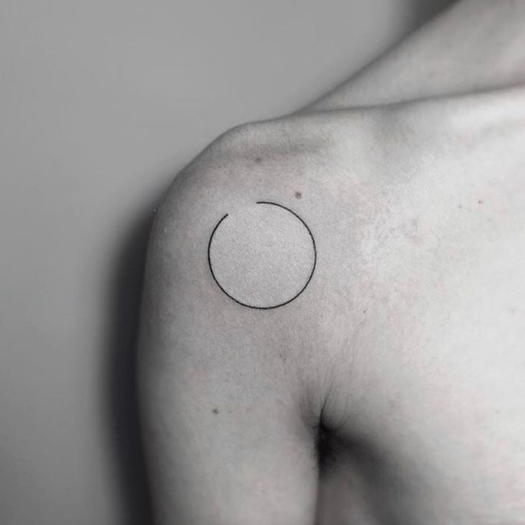 a black and white photo of a man's shoulder with a circle tattoo on it