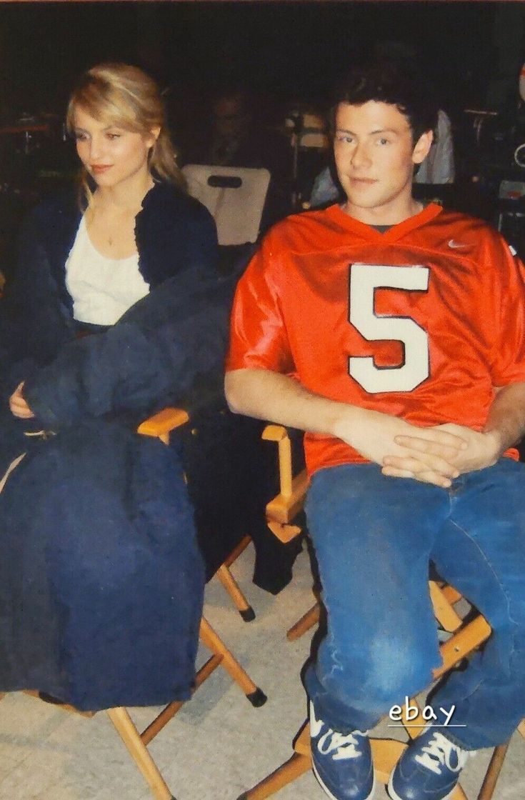 a young man and woman sitting next to each other in chairs with the number 5 on them