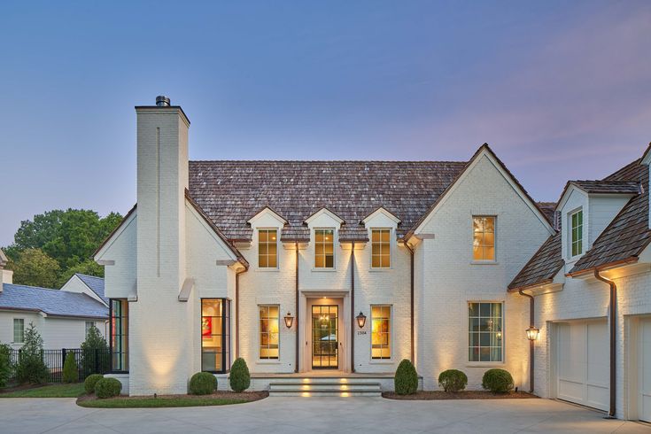 a large white house with lots of windows and lights on it's front door