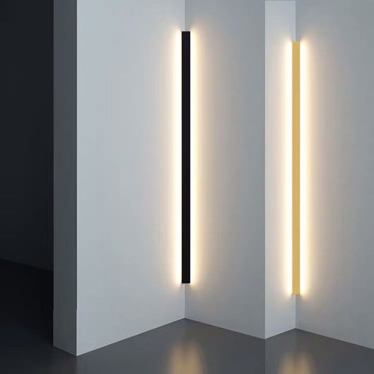 two lights that are next to each other in a room with white walls and black flooring