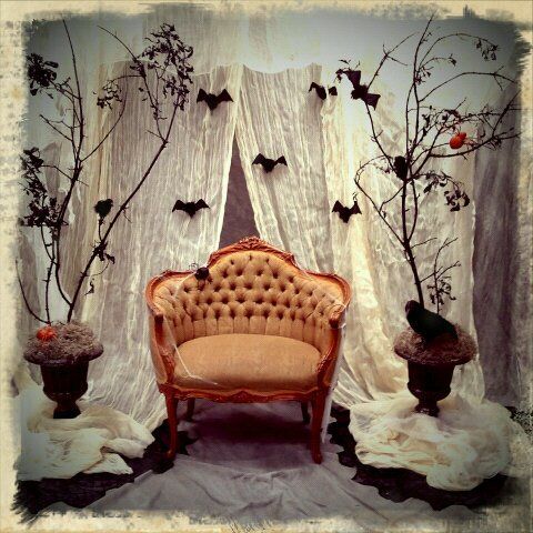 an old chair and two vases with bats on the wall behind it in front of a curtain