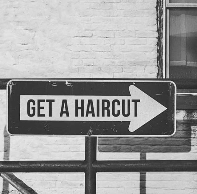 a black and white photo of a sign that says get a haircut on it