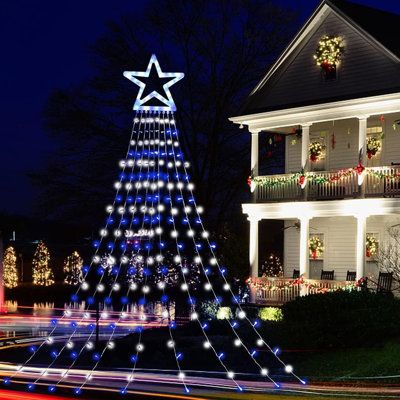 a lit up christmas tree in front of a house