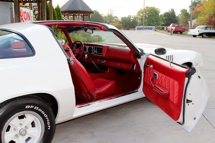 a white car with its door open and the driver's seat folded down in front of it