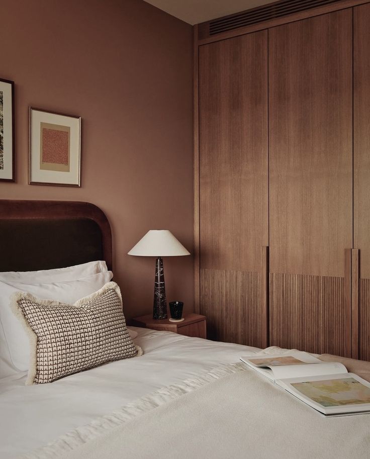 a bed with white sheets and pillows in a bedroom next to a wooden cabinet door