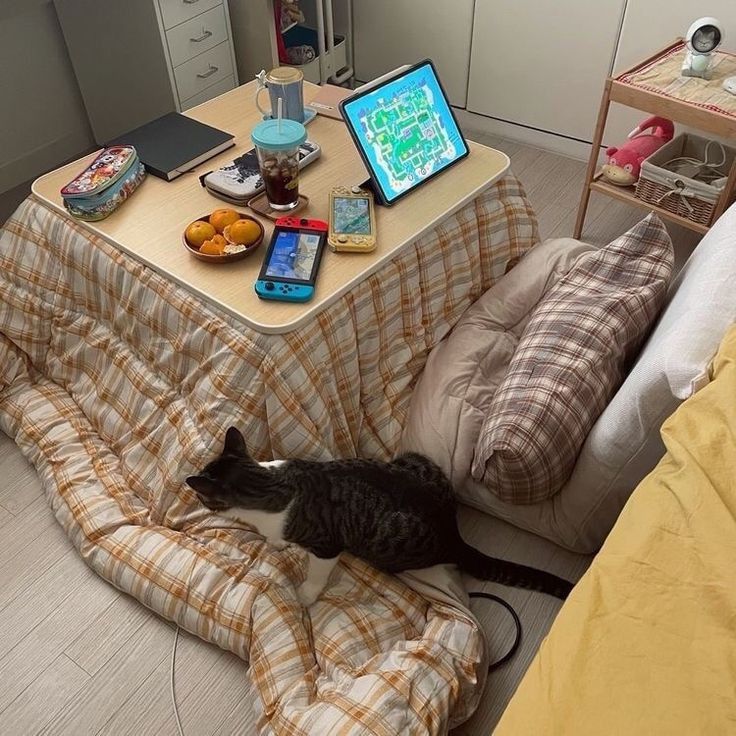 a cat laying on top of a bed next to a table