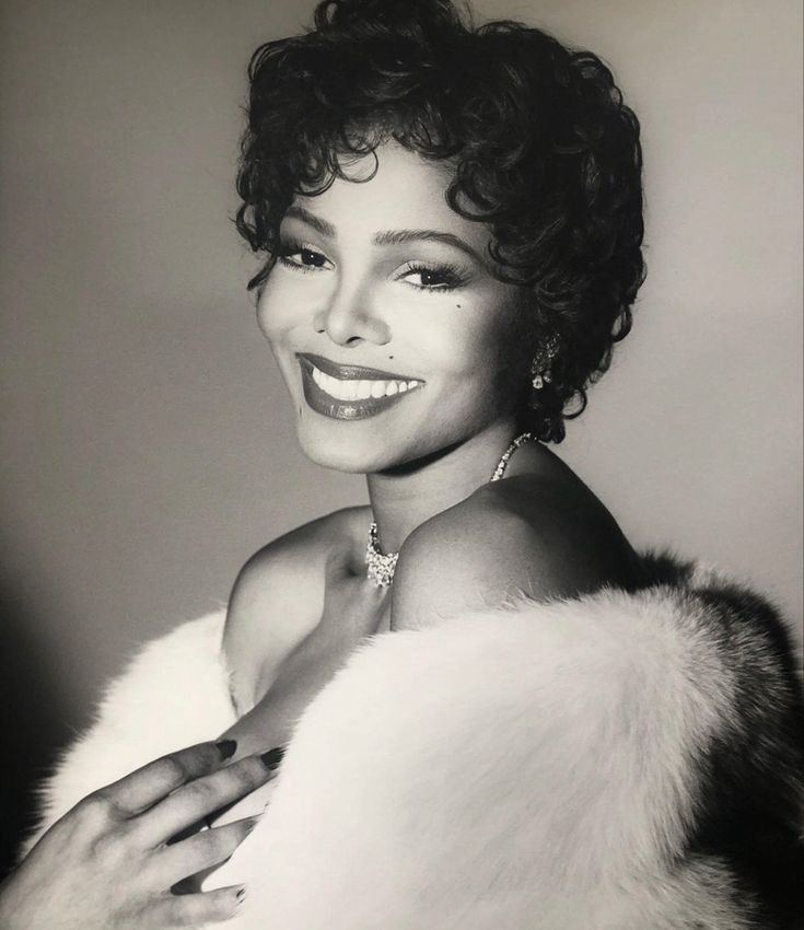 a black and white photo of a woman with a fur stole around her shoulders, smiling