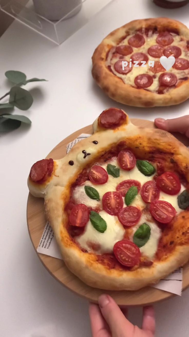 two small pizzas with toppings on wooden plates sitting on a white counter top