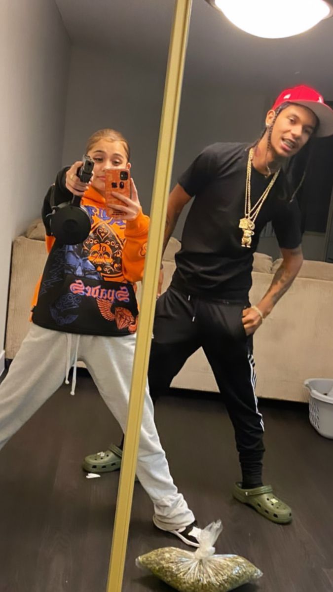 two people standing in front of a mirror with one person taking a selfie and the other holding a cell phone