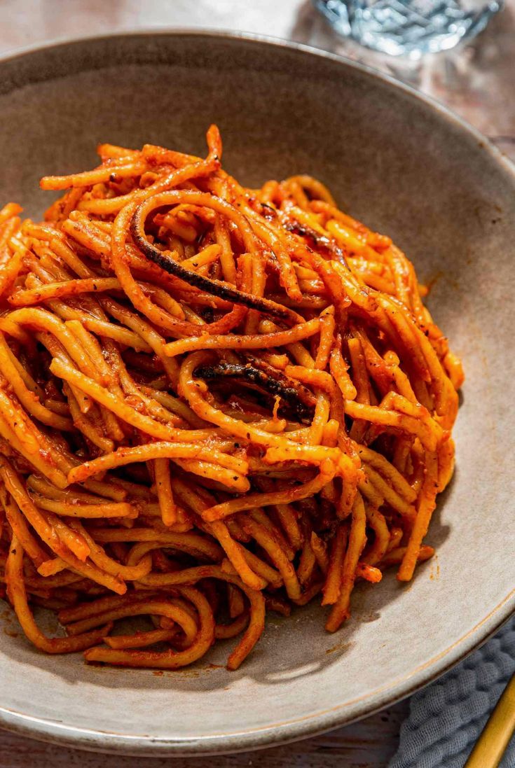 a bowl filled with pasta on top of a table next to two chopsticks