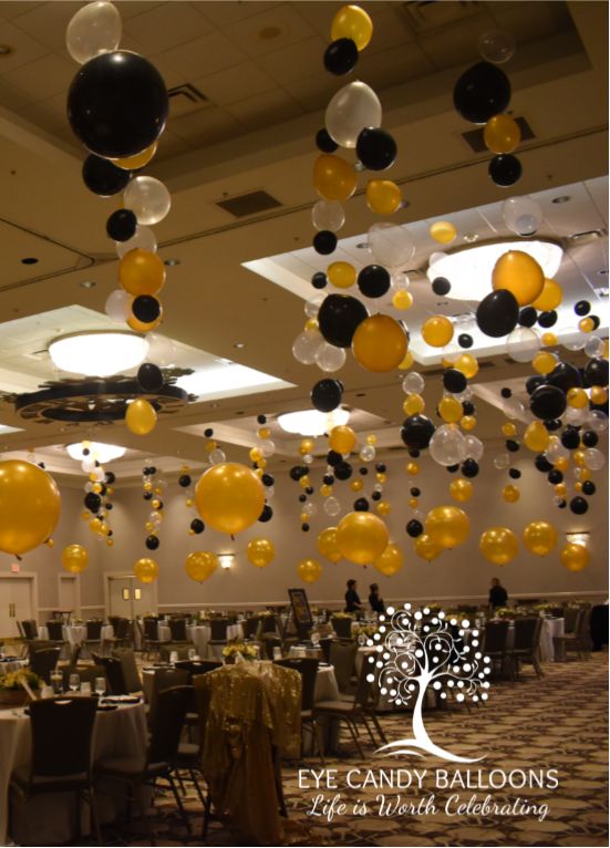 black and white balloons are hanging from the ceiling in a banquet hall with tables set for an event