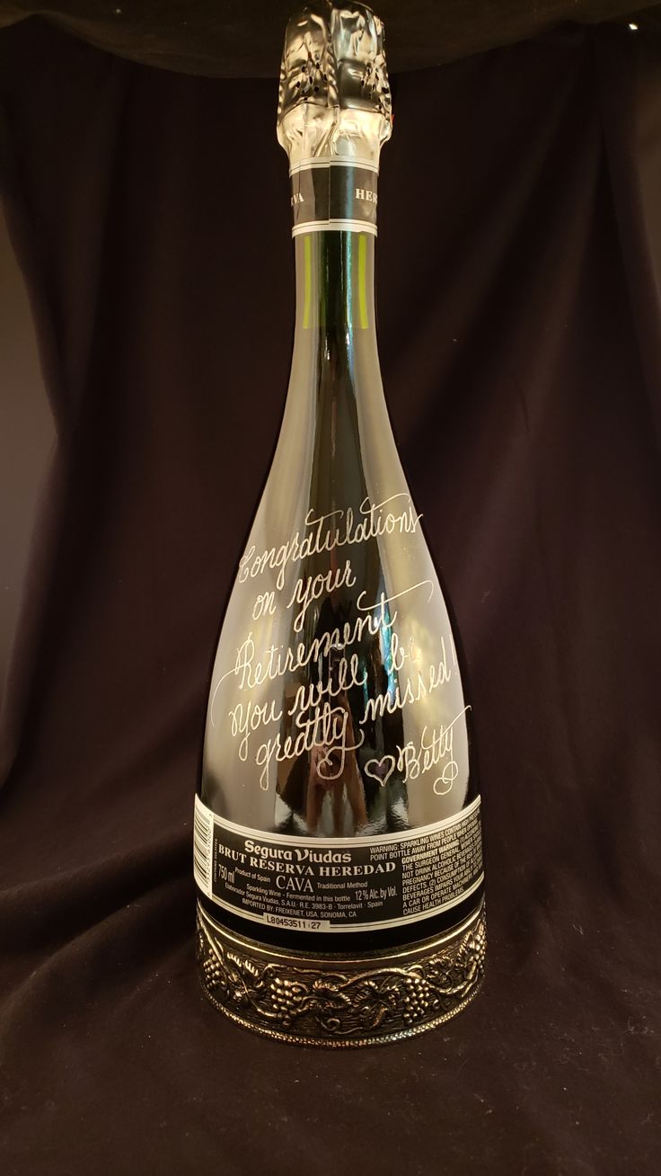 a glass bottle with writing on it sitting on a black cloth covered tableclothed surface