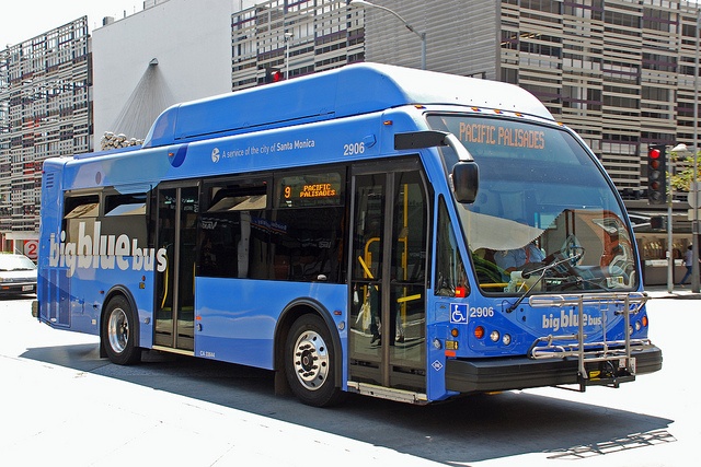 a blue bus is parked on the side of the road in front of tall buildings