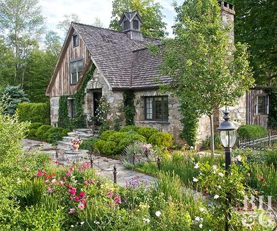 a stone house surrounded by flowers and trees