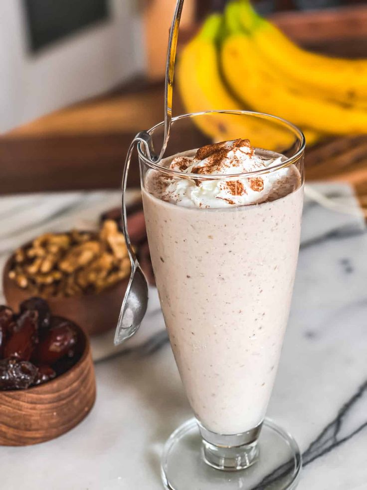 a glass filled with food sitting on top of a table next to fruit and nuts