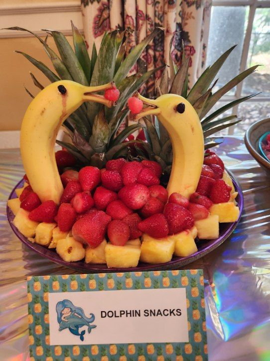 two birds made out of strawberries and bananas on a plate with a name tag