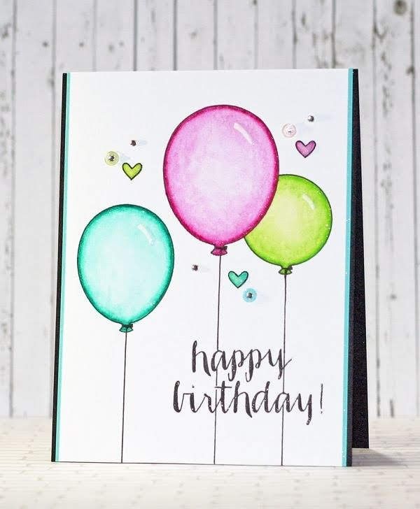 a birthday card with balloons and hearts on the front, sitting next to a wooden table