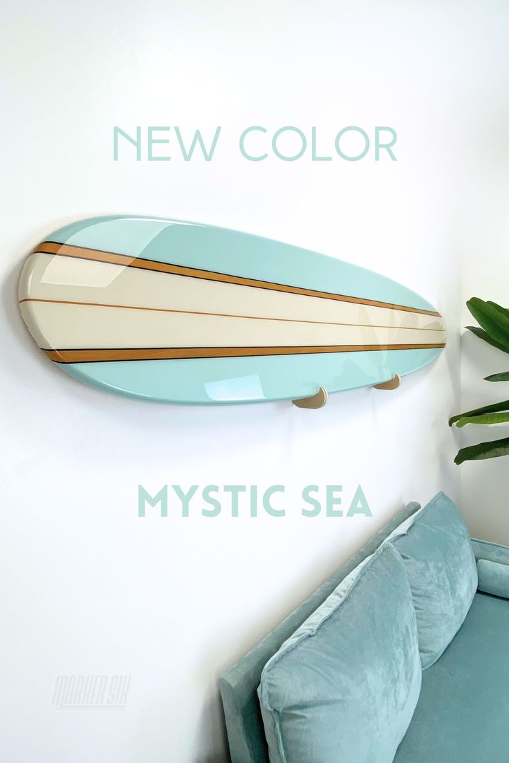 a surfboard mounted to the wall next to a blue couch and potted plant