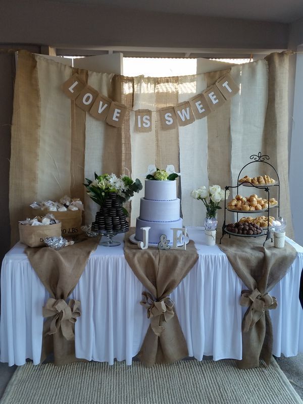 a table topped with a cake next to a window covered in burlaps