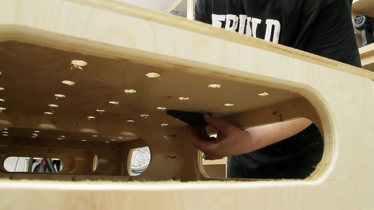 a young boy is working on something in a wooden structure that looks like a boat