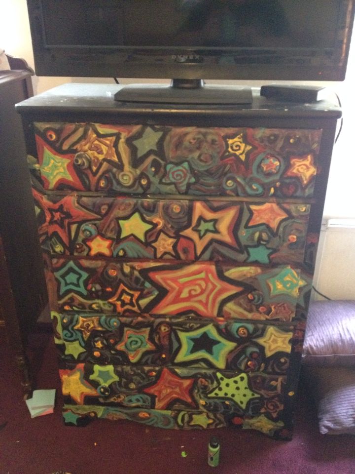 an old dresser has been painted with colorful stars on it and is sitting in front of a flat screen tv