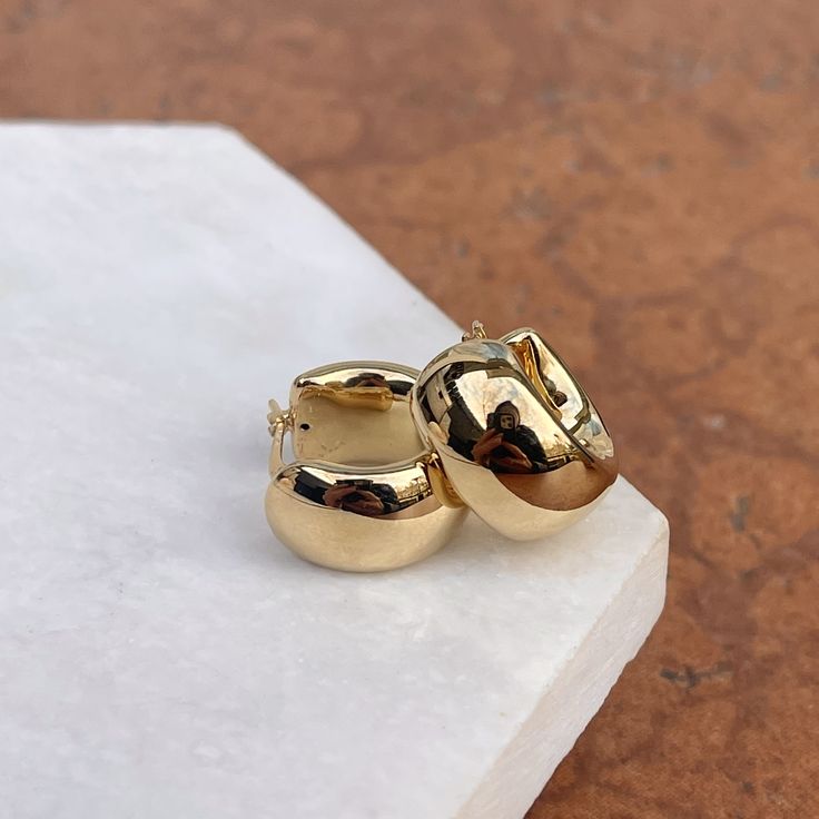 14KT yellow gold wide + chunky huggie hoop earrings. Small size hoops that fit closer to the lobe. Yummy chunkiness to these hoops! Huggies/Hoop style as they "hug" the earlobe. Length: 18mm Thickness: 9mm Weight: 2.83 grams Stamped 14K One pair Hollow hoops Wire + clutch backs Gold Hoped Earrings, Luxury Gold Plated Earrings For Everyday, Luxury Brass Small Hoop Huggie Earrings, Gold Fill Hoop Earrings, Small Gold Thick Hill Earrings, Bulk Gold Earrings, Cheap Classic Gold Plated Earrings, Affordable Yellow Gold Brass Earrings, Cheap Classic Gold-plated Earrings