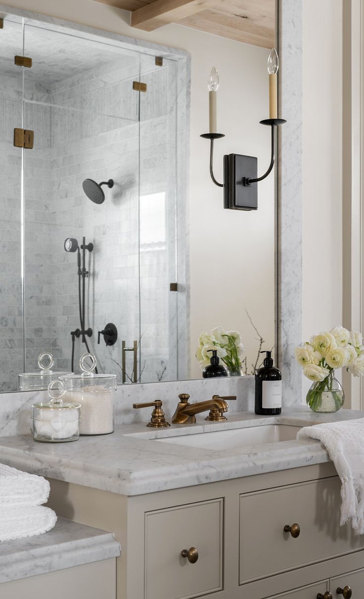 a bathroom with marble counter tops and white towels on the sink, along with candles